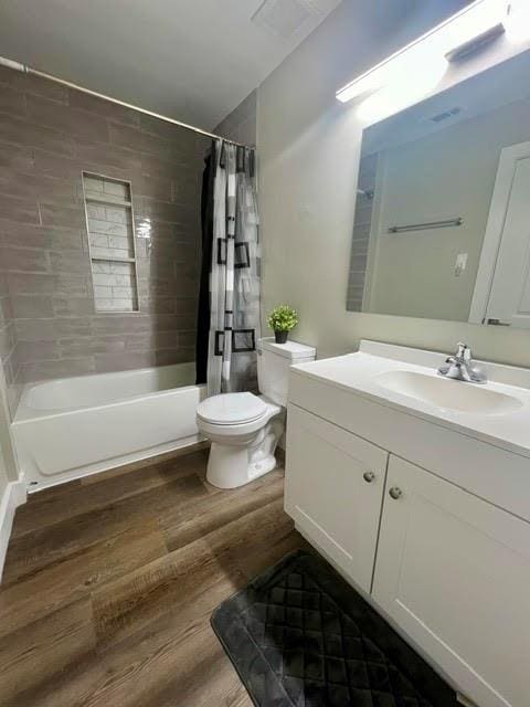 full bathroom featuring shower / bathtub combination with curtain, hardwood / wood-style flooring, vanity, and toilet