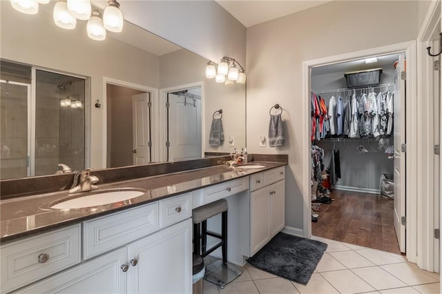 bathroom featuring double vanity, a sink, a walk in closet, and tile patterned floors