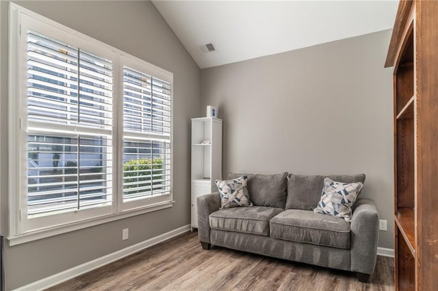 living area featuring vaulted ceiling, wood finished floors, visible vents, and baseboards