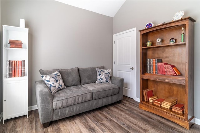 living area with dark wood-style floors, baseboards, and vaulted ceiling