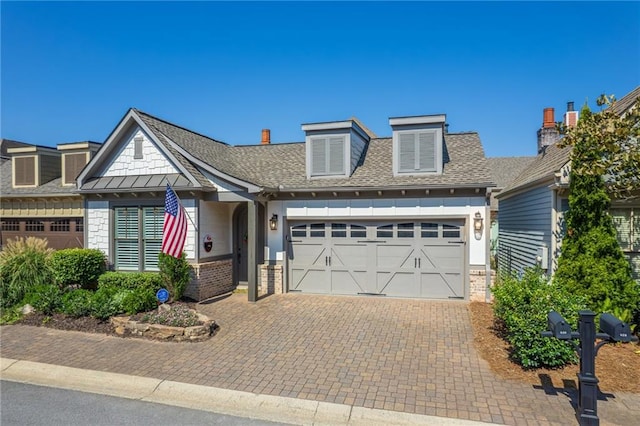 view of front of house with a garage, brick siding, decorative driveway, and a shingled roof