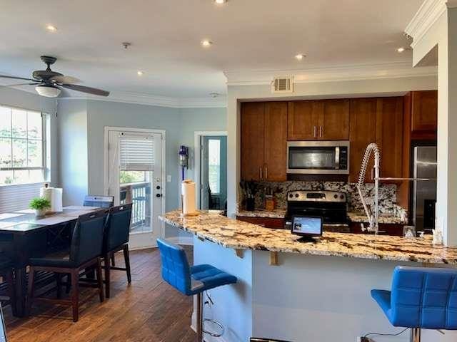200 Renaissance Pkwy NE Unit 304, Atlanta, GA 30308 - kitchen with stainless steel appliances, light stone counters, crown molding, dark wood-type flooring, and a kitchen breakfast bar