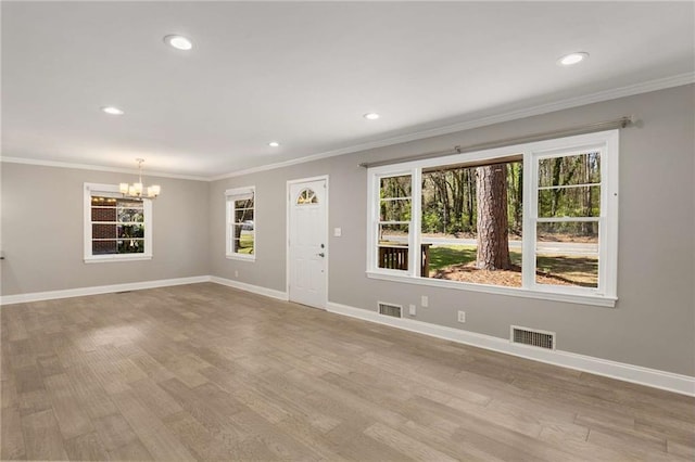 unfurnished living room featuring a healthy amount of sunlight, visible vents, and a chandelier