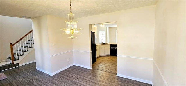 interior space with a textured ceiling, sink, dark wood-type flooring, and a chandelier