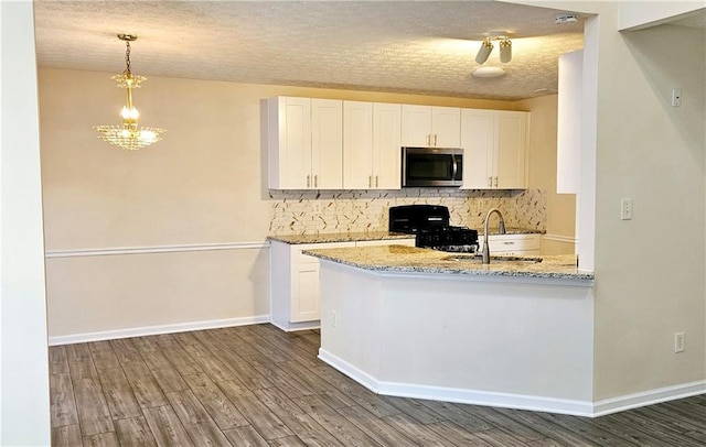 kitchen with white cabinets, dark hardwood / wood-style flooring, black range with gas stovetop, and a textured ceiling