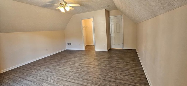 additional living space featuring lofted ceiling, a textured ceiling, and hardwood / wood-style flooring