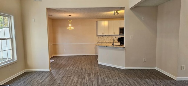 kitchen with white cabinets, light stone counters, dark wood-type flooring, and a textured ceiling