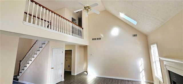 unfurnished living room with dark hardwood / wood-style flooring, high vaulted ceiling, and ceiling fan