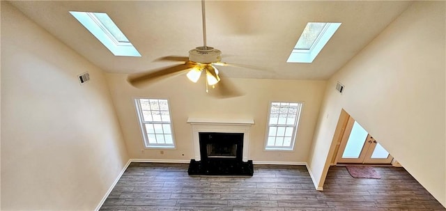 unfurnished living room featuring a wealth of natural light, ceiling fan, and dark wood-type flooring