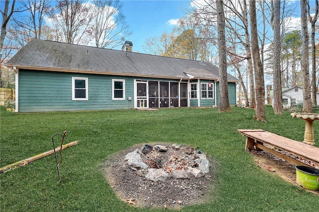 back of property featuring a sunroom, an outdoor fire pit, and a lawn