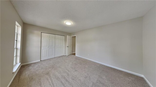 unfurnished bedroom with carpet floors, baseboards, and a textured ceiling