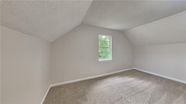 bonus room featuring baseboards, carpet flooring, a textured ceiling, and vaulted ceiling