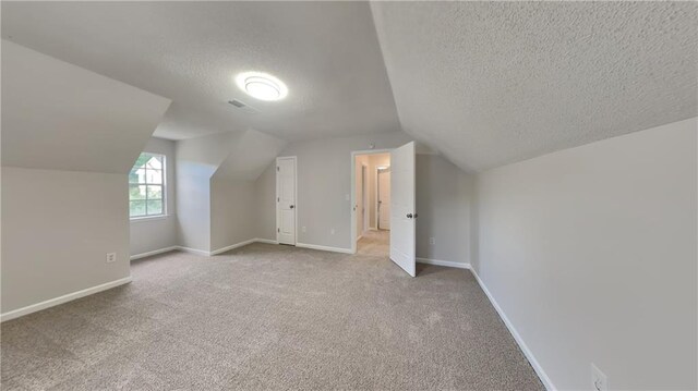 additional living space featuring carpet flooring, a textured ceiling, baseboards, and lofted ceiling
