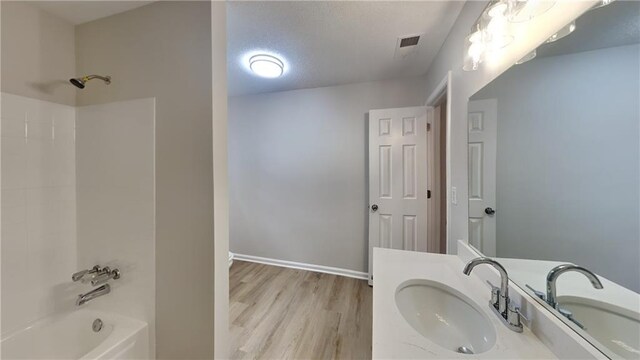 full bathroom with shower / bathing tub combination, a textured ceiling, visible vents, wood finished floors, and baseboards