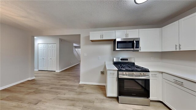 kitchen with light countertops, a textured ceiling, white cabinets, and stainless steel appliances