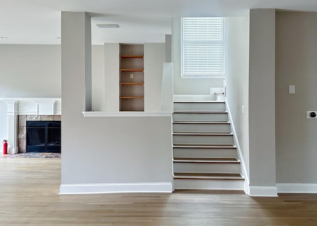 stairs featuring a fireplace, baseboards, and wood finished floors