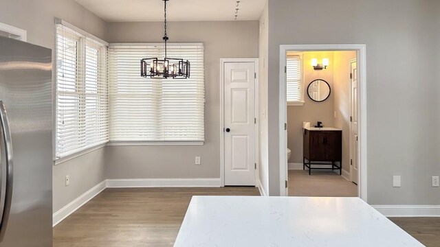 unfurnished dining area featuring a notable chandelier, baseboards, and wood finished floors