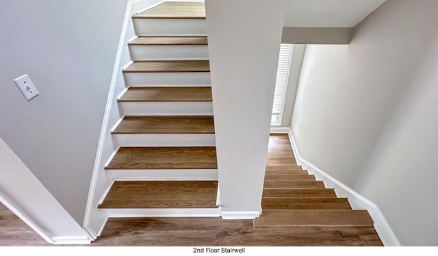 staircase featuring baseboards and wood finished floors