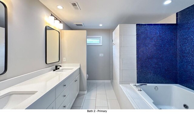 bathroom featuring toilet, a tub with jets, visible vents, and a sink