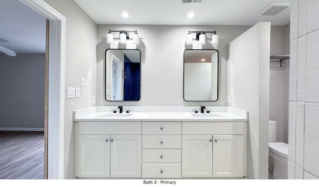 full bath with visible vents, a sink, toilet, and double vanity