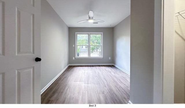 unfurnished room featuring ceiling fan, wood finished floors, visible vents, and baseboards