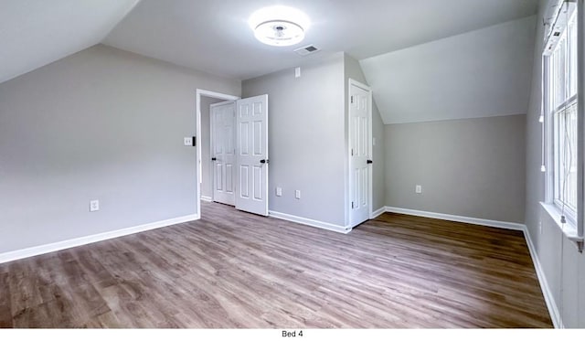 bonus room with lofted ceiling, visible vents, baseboards, and wood finished floors