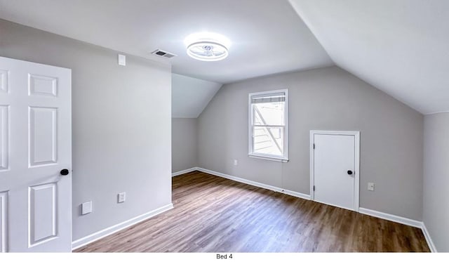 additional living space featuring lofted ceiling, wood finished floors, visible vents, and baseboards