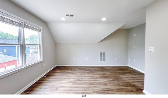 additional living space featuring lofted ceiling, visible vents, baseboards, and wood finished floors