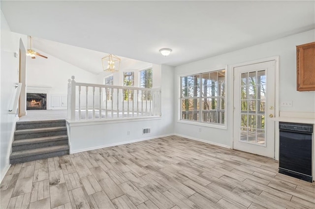 unfurnished living room with a wealth of natural light, visible vents, a lit fireplace, and light wood finished floors