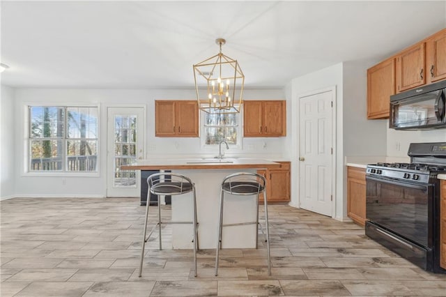 kitchen featuring black appliances, pendant lighting, a kitchen breakfast bar, an inviting chandelier, and light countertops