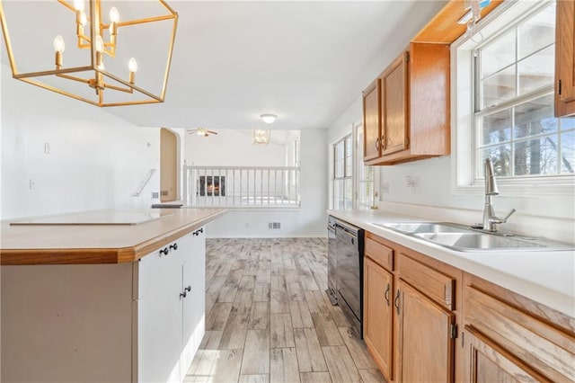 kitchen featuring ceiling fan, a sink, light countertops, black dishwasher, and light wood-type flooring