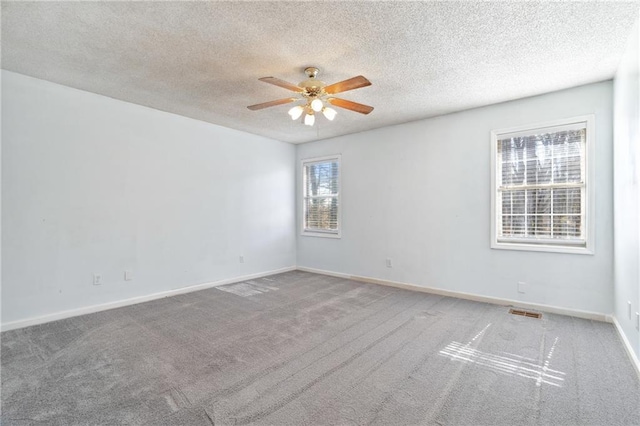 carpeted empty room with visible vents, baseboards, a textured ceiling, and ceiling fan