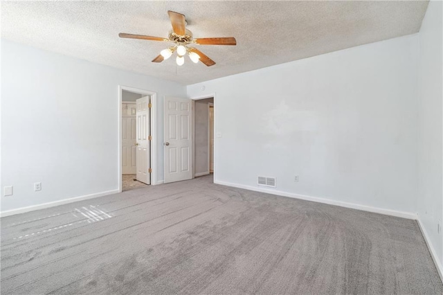 carpeted empty room featuring ceiling fan, baseboards, visible vents, and a textured ceiling