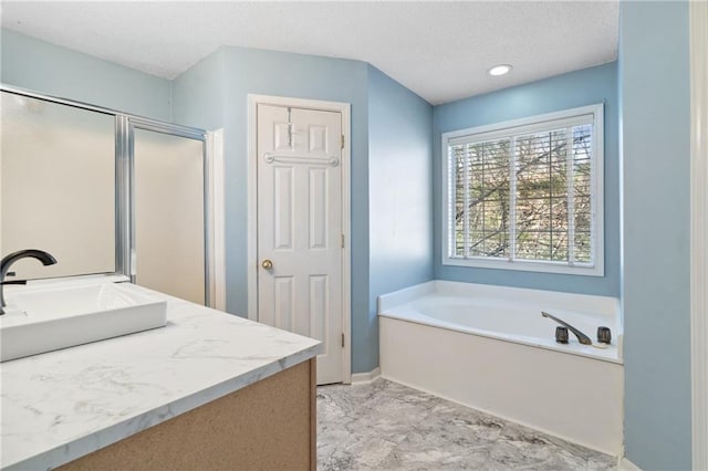 bathroom with a shower stall, a textured ceiling, a garden tub, and a sink