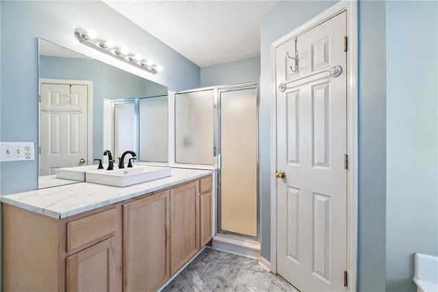 bathroom with a shower stall, a textured ceiling, and vanity