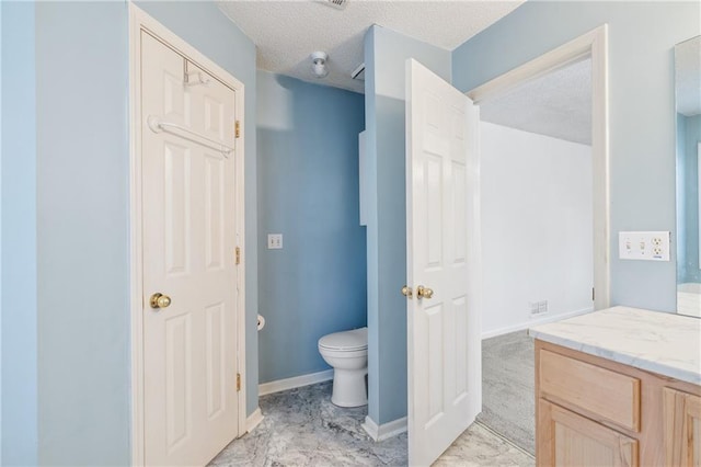 bathroom featuring a textured ceiling, toilet, vanity, and baseboards