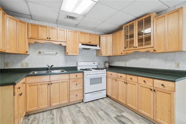 kitchen featuring visible vents, under cabinet range hood, light brown cabinetry, white range with gas cooktop, and a sink