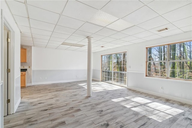 spare room featuring light wood finished floors, visible vents, a paneled ceiling, and baseboards