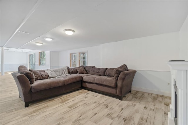 living room with light wood-style flooring, a fireplace, and baseboards