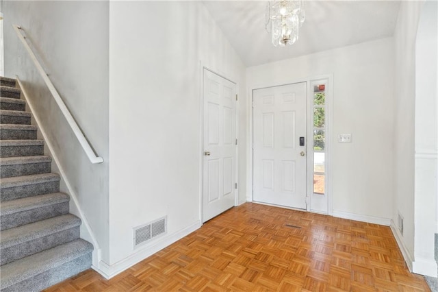 entrance foyer with an inviting chandelier, stairway, baseboards, and visible vents