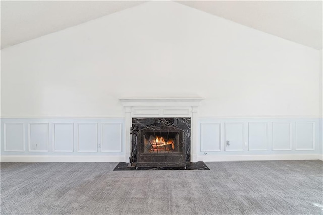 interior details featuring a premium fireplace, a decorative wall, and carpet floors