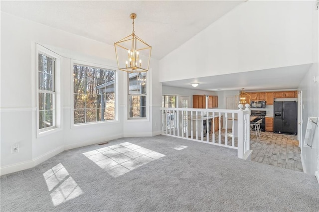 unfurnished dining area with light carpet, visible vents, baseboards, and an inviting chandelier