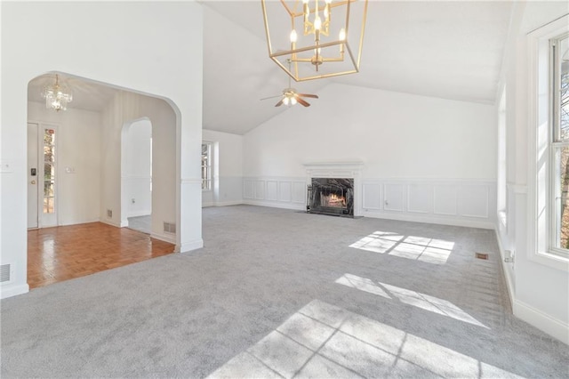 unfurnished living room with a high end fireplace, a decorative wall, arched walkways, and carpet floors