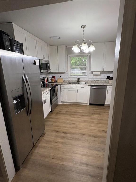 38 Daniel Cir, Franklin, GA 30217 - kitchen featuring appliances with stainless steel finishes, a sink, a chandelier, white cabinetry, and decorative backsplash