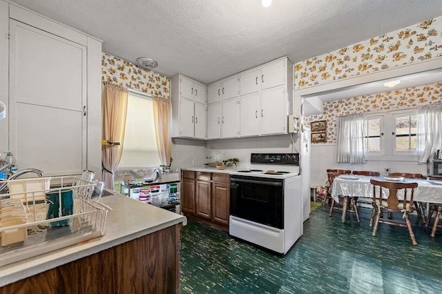 kitchen with electric stove, white cabinetry, and a textured ceiling