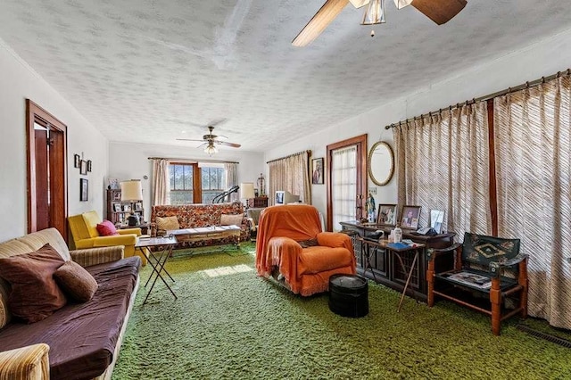 carpeted living room featuring ceiling fan and a textured ceiling