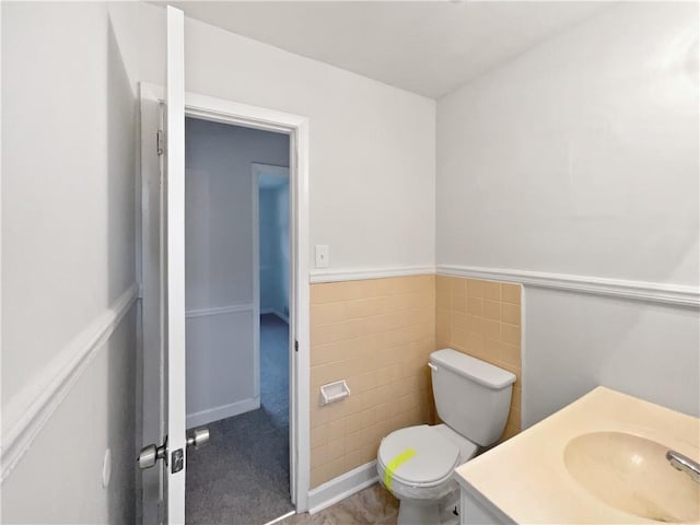 bathroom with vanity, tile walls, and toilet