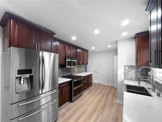 kitchen featuring appliances with stainless steel finishes, sink, light hardwood / wood-style floors, and decorative backsplash