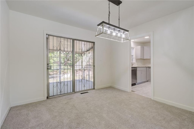 unfurnished dining area with a sink, visible vents, light carpet, and baseboards