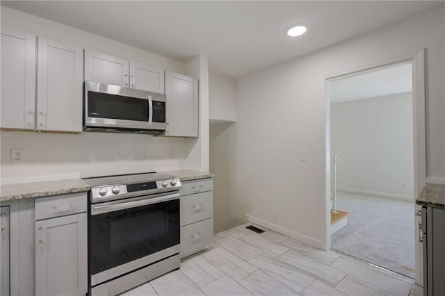 kitchen with light stone counters, visible vents, stainless steel appliances, and baseboards